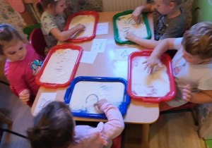 Dzieci dokonały wyboru obrazka który będą malować na mące za pomocą paluszka.